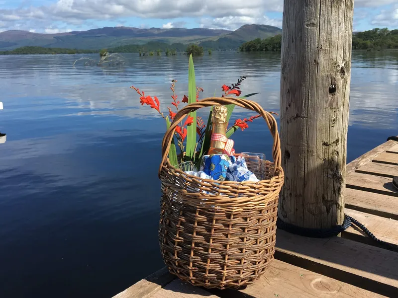 A wicker basket holding champagne and glasses on the pier at Portnellan