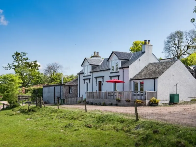 The Old Farmhouse seen across the farm track, with its front deck and a red parasol