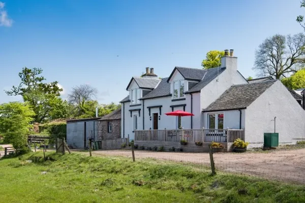 The Old Farmhouse seen across the farm track, with its front deck and a red parasol