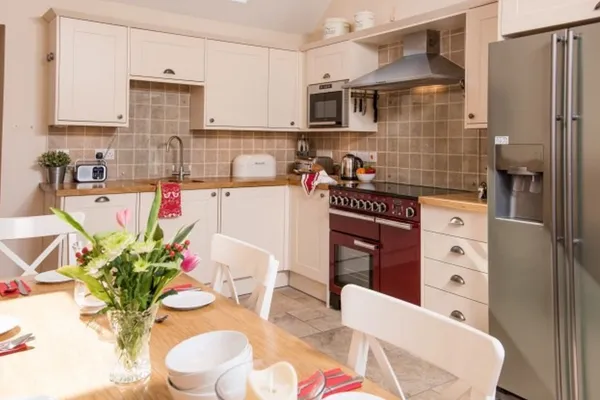 The kitchen, with a red Rangemaster cooker and a dining table set with tulips