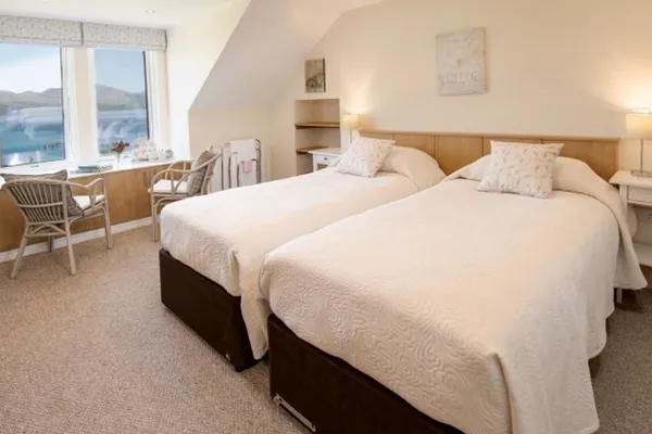 Two single beds side by side in a bedroom with loch-facing windows