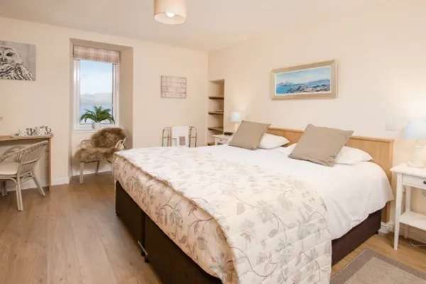 A double bed in a bedroom with a window onto the loch